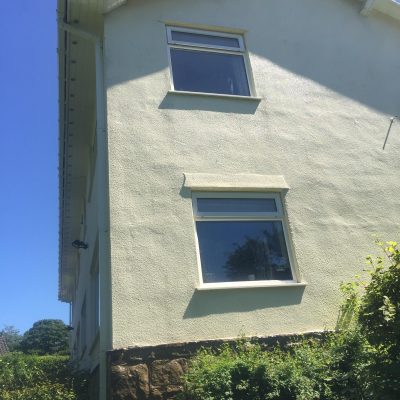 rendered gable after professional cleaning, with the staining removed and the pale finish restored.