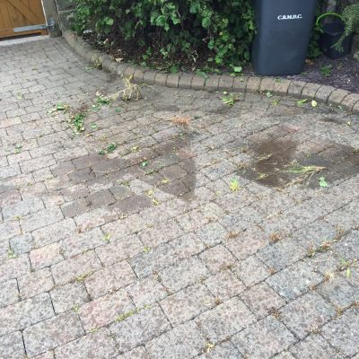 Weeds and loose vegetation being cleared from an aged block-paved driveway before cleaning in Wharfedale.