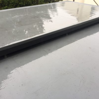 Freshly cleaned grey flat roof surrounding a raised rooflight, with the surface cleared of accumulated debris.