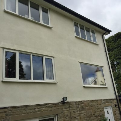 The same two-storey rendered wall after cleaning, with the algae streaking removed and its light finish restored.