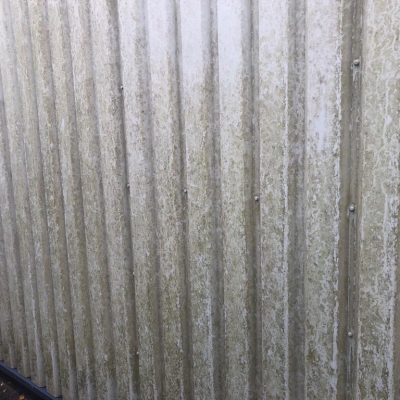 cladding covered in mottled grey staining and ingrained surface contamination before restoration.
