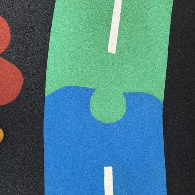 Green and blue wet-pour playground surface after cleaning, with clear white road markings.