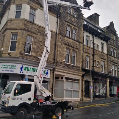 High-level gutter clearing from a truck-mounted access platform on a stone town-centre building in Wharfedale.