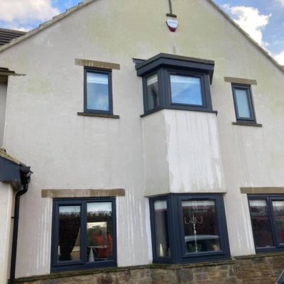 Green algae and rainwater streaks on house render before softwash cleaning in Leeds.