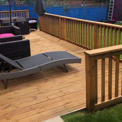 Grooved timber decking and balustrades finished with a warm golden-brown stain and furnished with outdoor seating and a sun lounger.